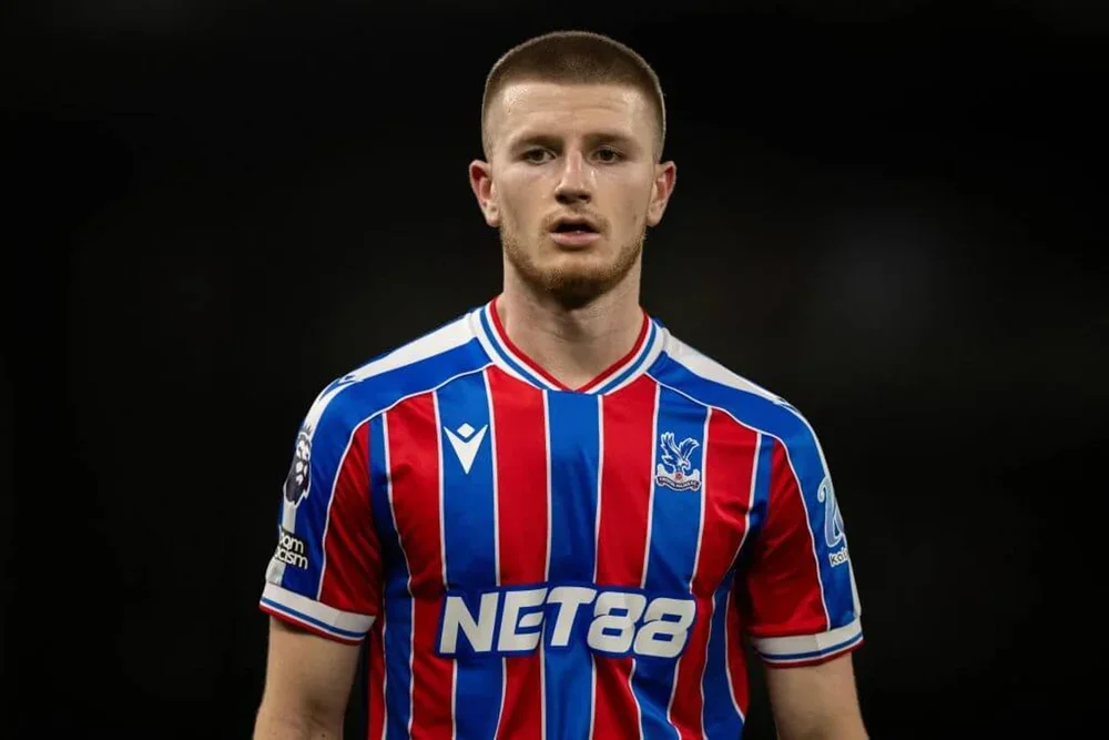Adam Wharton stares straight ahead while wearing the disctinctive blue and red home shirt of Crystal Palace